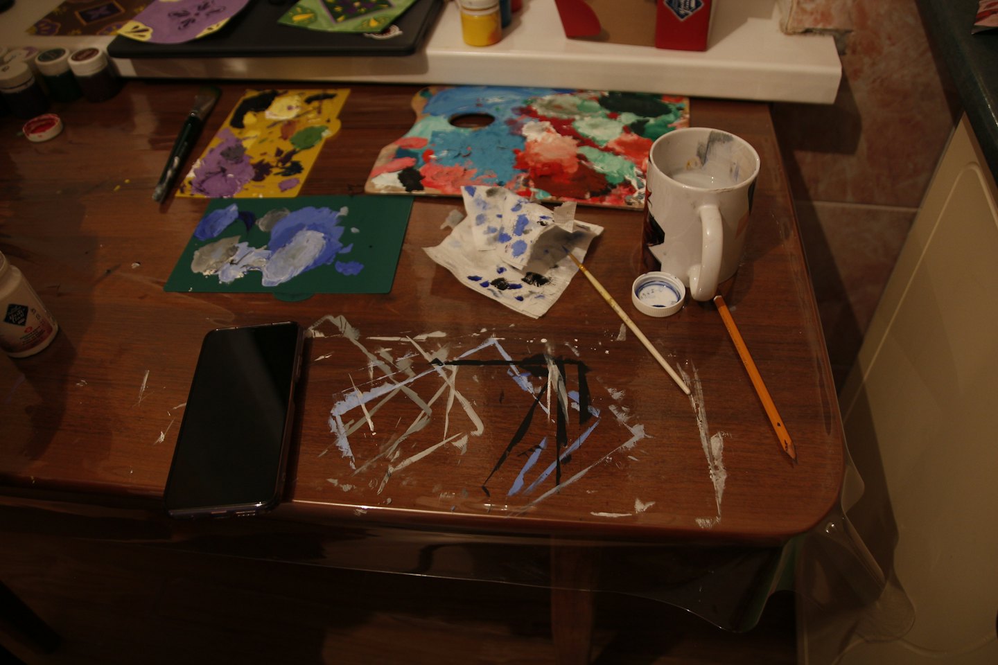 Art supplies and paint palettes scattered on a wooden table.