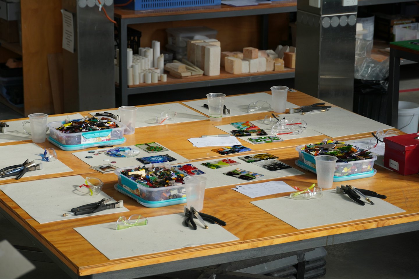 Glass art class stations with colorful shards and tools.