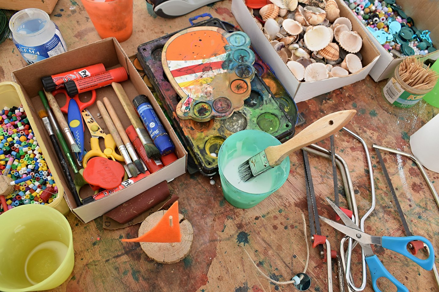 Wooden craft table filled with beads, paint, and a sailboat.