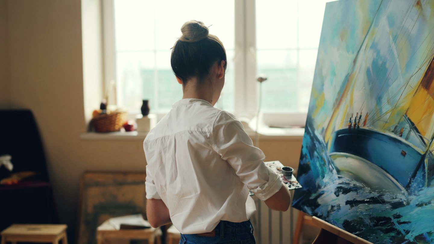 Artist paints a seascape on a canvas in her studio.