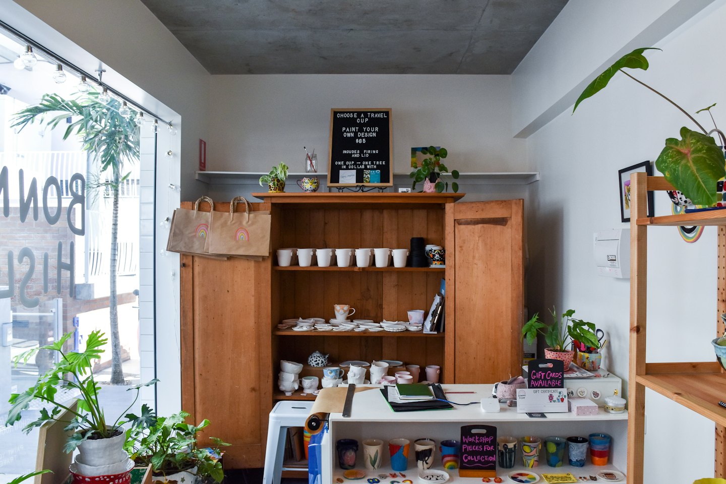 Pottery studio with unpainted ceramics on shelves and finished pieces on counter.